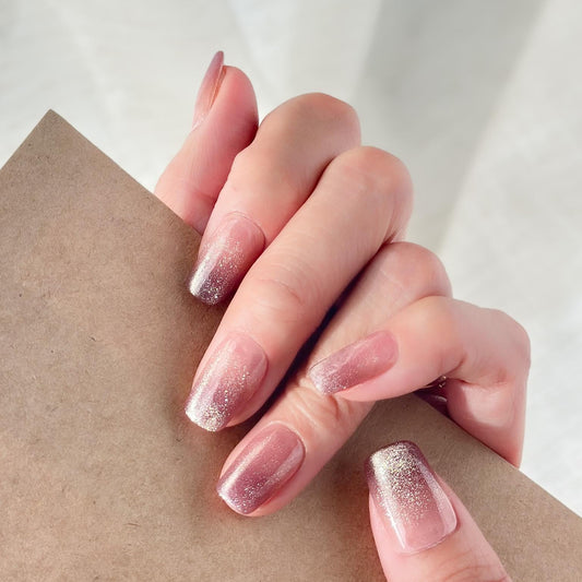 Hand with Short square pink mauve ombré press-on nails with fine glitter shimmer, soft blush gradient, and glossy finish
