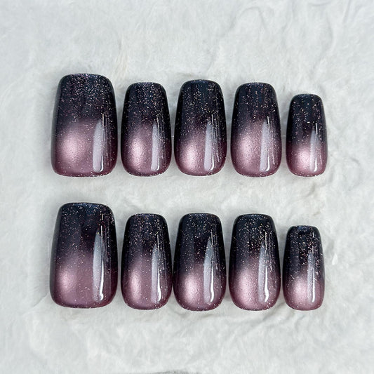 Short square press-on nails in a deep plum purple cat-eye shimmer with black gradient edges and silver sparkle accents