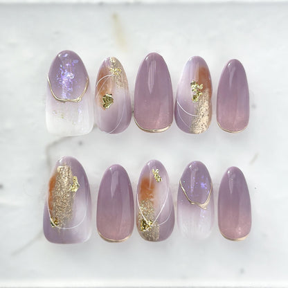 Almond shape purple press-on nails with gold foil accents and soft gradient shimmer. Elegant reusable salon-style press on nails by ManiFleur, featuring lavender ombré, metallic details, and glossy finish