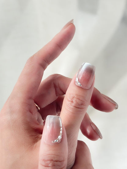 Hand with Square shape pink ombré press-on nails with silver cat-eye shimmer and rhinestone accents