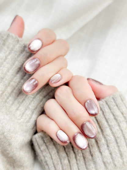 Short oval press-on nails in a metallic mauve cat-eye shimmer, glossy finish, luxury reusable press-on manicure by ManiFleur. Elegant mauve shimmer nails styled against a cozy knit sweater