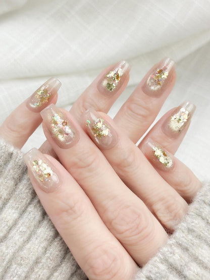 Hand with Press on nail with nude base and crushed foil glitter accent in gold, artificial nails