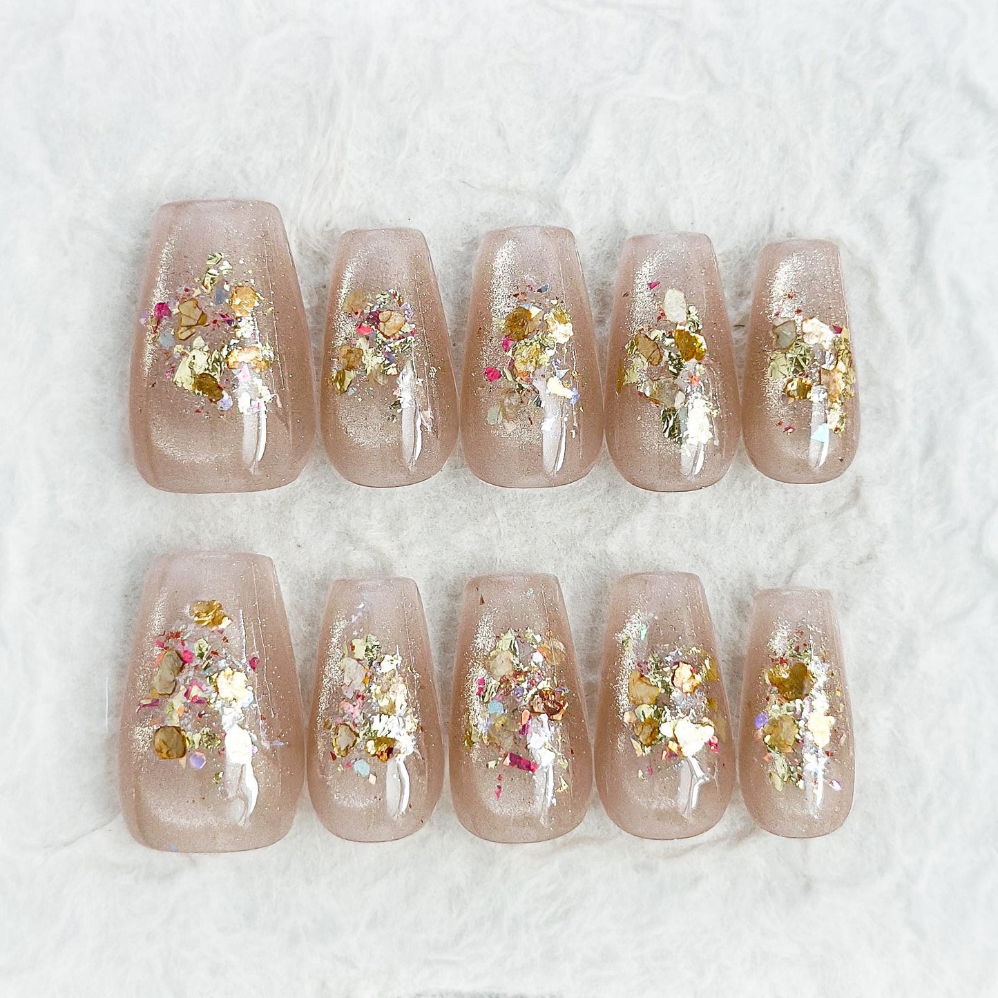 Press on nail with nude base and crushed foil glitter accent in gold, artificial nails