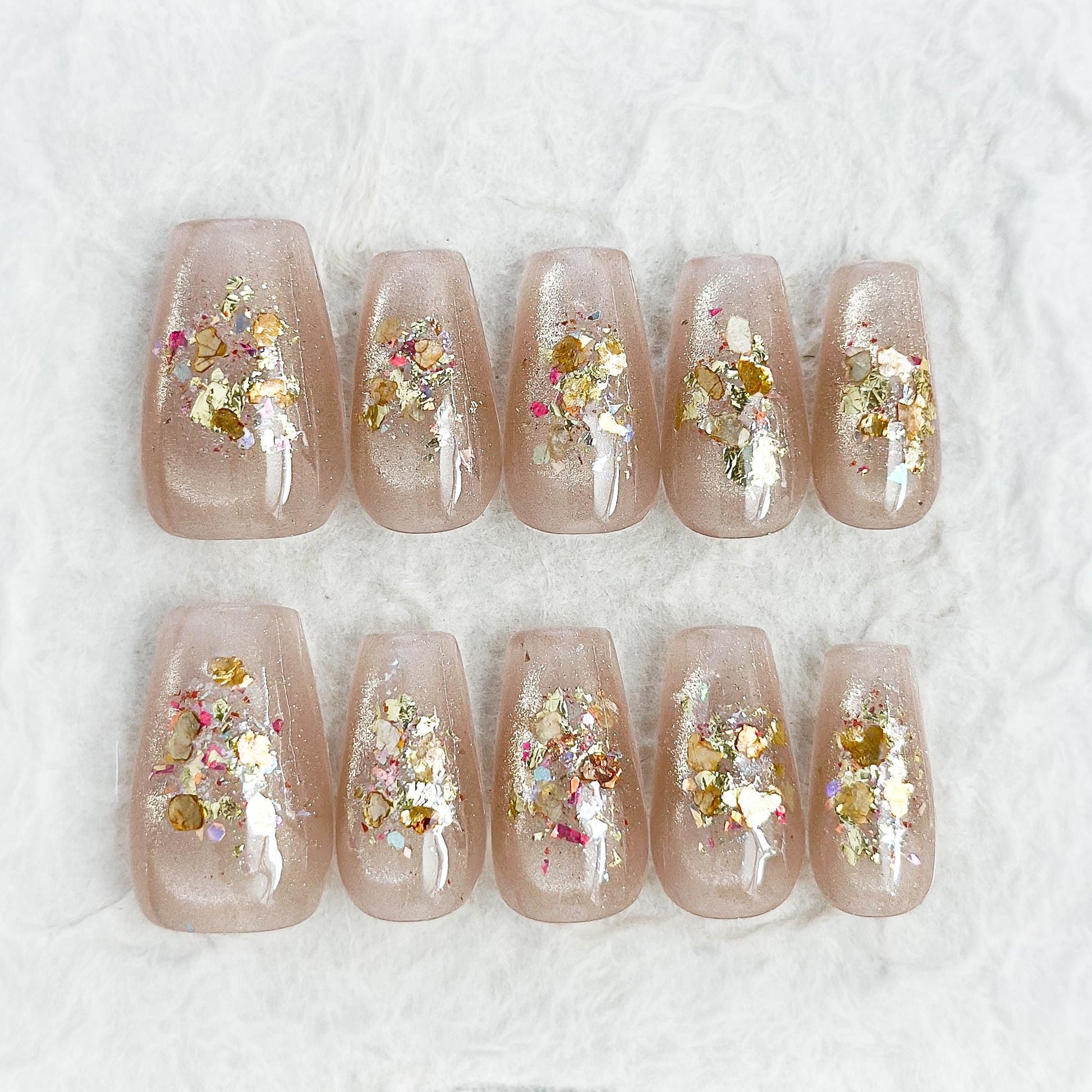 Press on nail with nude base and crushed foil glitter accent in gold, artificial nails