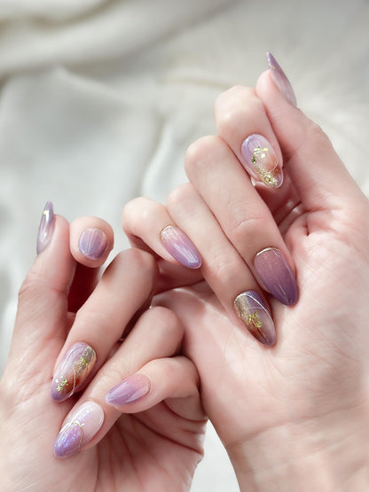 Almond shape purple press-on nails with gold foil accents and soft gradient shimmer. Elegant reusable salon-style press on nails by ManiFleur, featuring lavender ombré, metallic details, and glossy finish