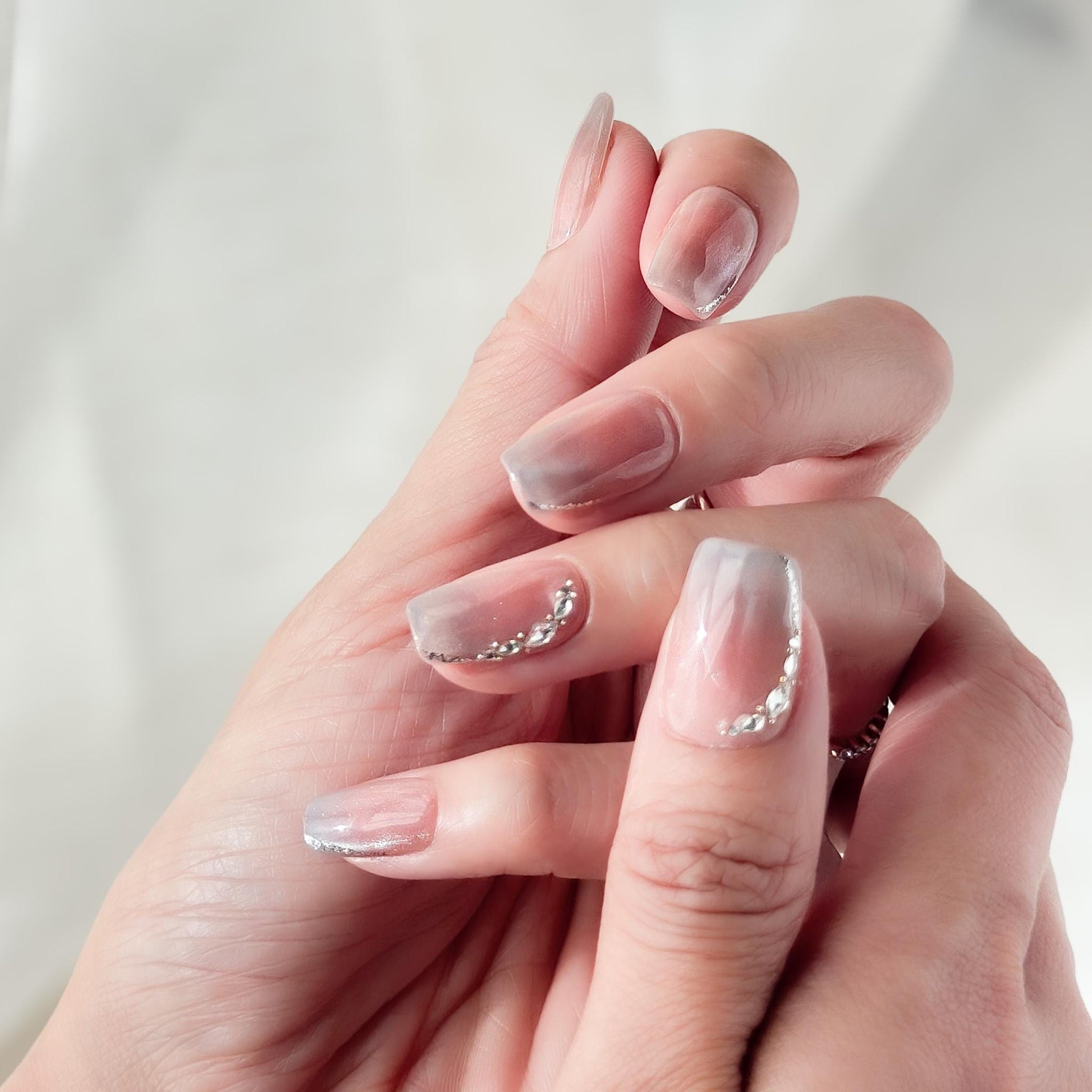 Hand with Square shape pink ombré press-on nails with silver cat-eye shimmer and rhinestone accents