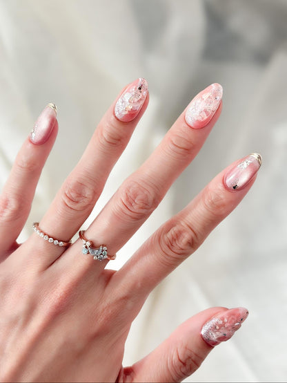 Hand with Pink shimmer press-on nails with iridescent glitter, marble swirl accents, and gold foil details