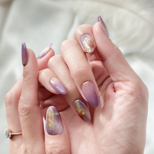 Almond shape purple press-on nails with gold foil accents and soft gradient shimmer. Elegant reusable salon-style press on nails by ManiFleur, featuring lavender ombré, metallic details, and glossy finish