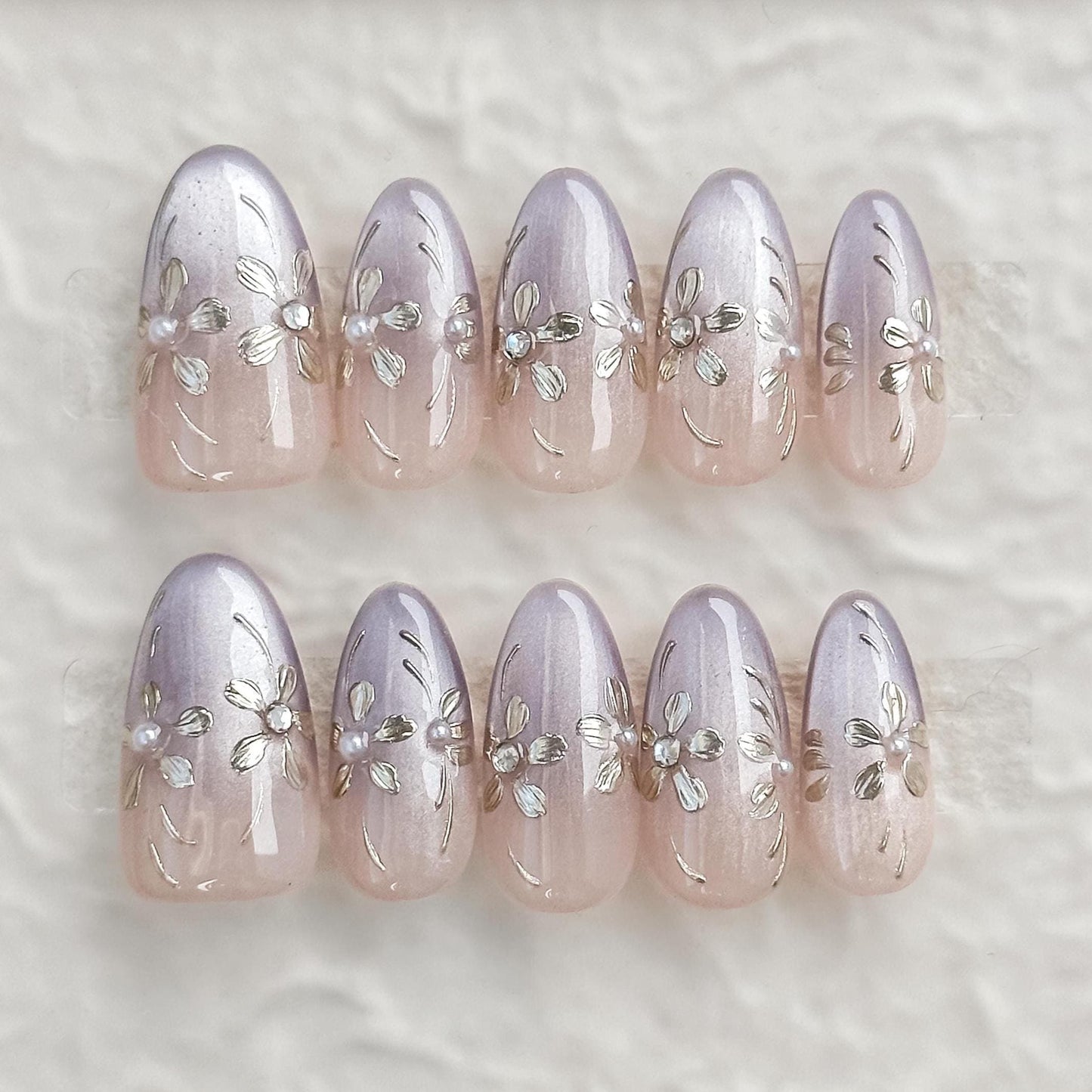 press on nails in light purple and nude ombre base with gold floral accents 