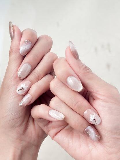 Hand with Pink and pearl white press-on nails with soft marble accents, hand-painted white floral art, silver glitter details, and glossy finish