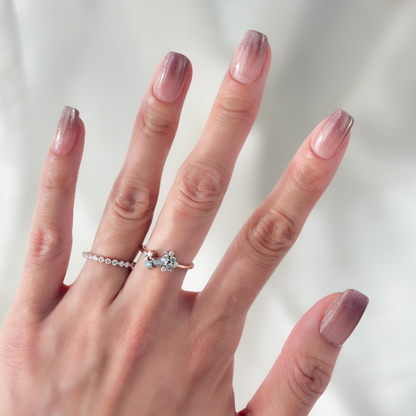 Hand with Short square pink mauve ombré press-on nails with fine glitter shimmer, soft blush gradient, and glossy finish