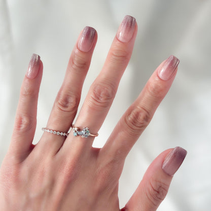 Hand with Short square pink mauve ombré press-on nails with fine glitter shimmer, soft blush gradient, and glossy finish