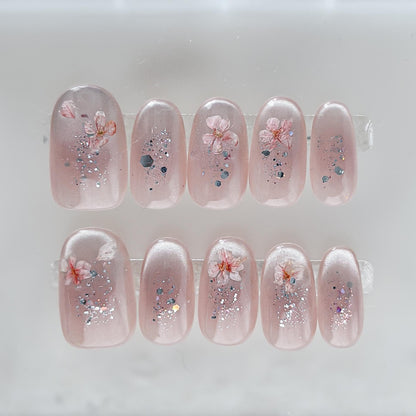 Press on nail made with real dried flowers encased in a translucent blush base with fine glitter