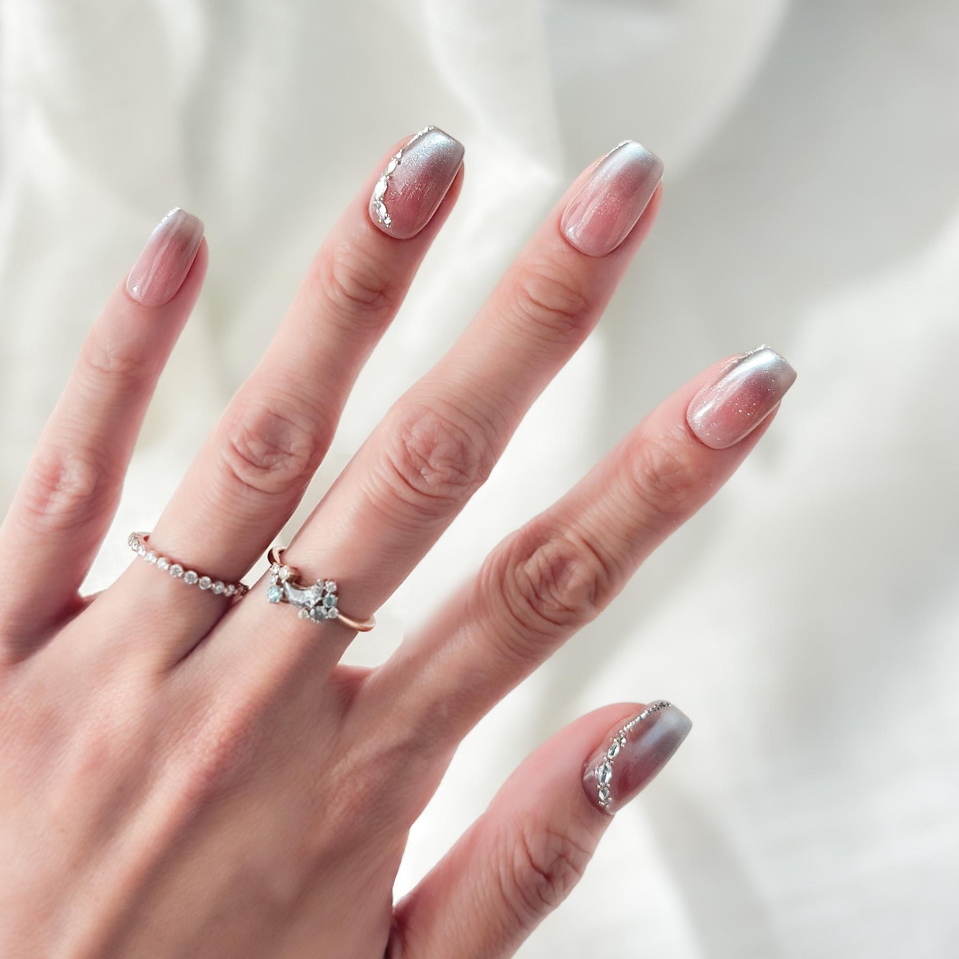 Hand with Square shape pink ombré press-on nails with silver cat-eye shimmer and rhinestone accents