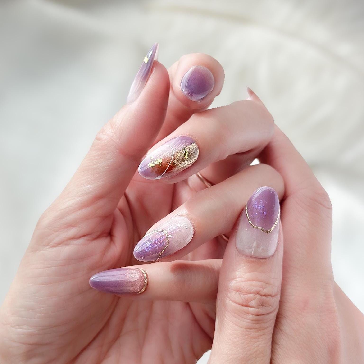 Almond shape purple press-on nails with gold foil accents and soft gradient shimmer. Elegant reusable salon-style press on nails by ManiFleur, featuring lavender ombré, metallic details, and glossy finish